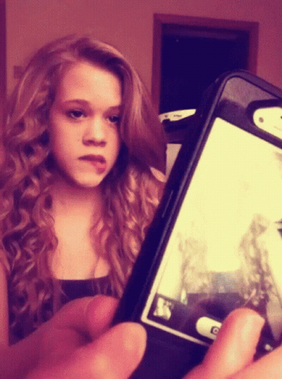A Young Girl Is Taking A Picture Of Herself On Her Phone GIF