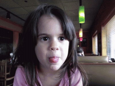 A Young Girl Sticking Her Tongue Out In A Restaurant GIF