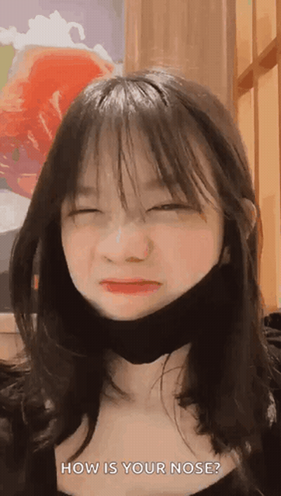 A Young Girl Wearing A Black Mask Is Making A Funny Face . GIF