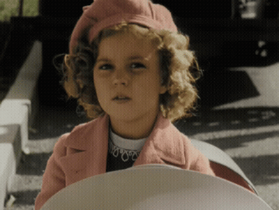 A Young Girl Wearing A Pink Coat And A Red Hat GIF