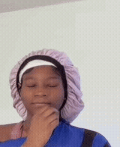 a young girl wearing a purple hat and a blue shirt is looking at the camera .