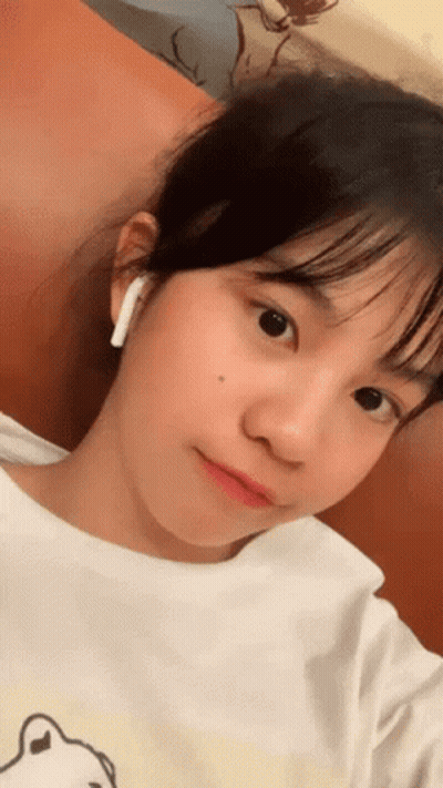A Young Girl Wearing A White Shirt And Ear Buds GIF