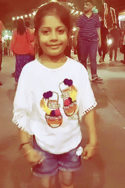 A Young Girl Wearing A White Shirt With A Picture Of Shoes On It GIF