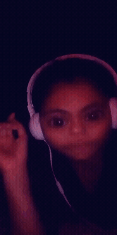 A Young Girl Wearing Headphones Is Smiling And Making A Funny Face GIF