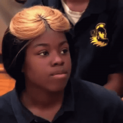 A Young Girl With Blonde Hair Is Making A Funny Face While Wearing A Blue Shirt . GIF