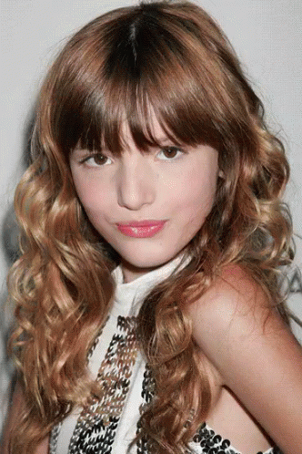 A Young Girl With Long Brown Hair And A White Top GIF