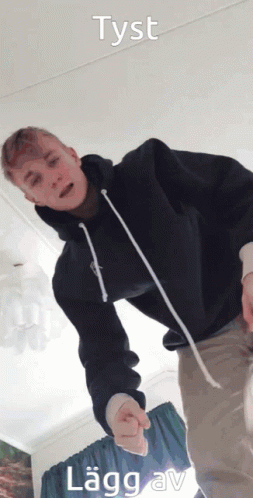 A Young Man In A Black Hoodie Is Standing In A Room With The Words Tyst Lagg Av Written Above Him GIF