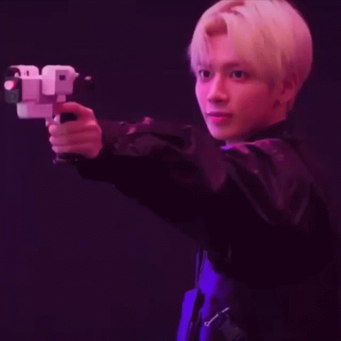 A Young Man In A Black Jacket Is Holding A Gun In His Hand . GIF
