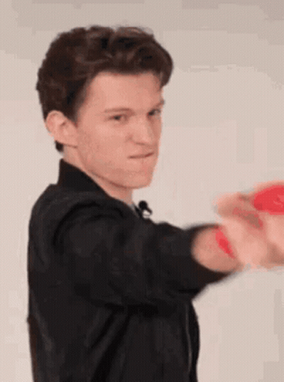 A Young Man In A Black Jacket Is Holding A Red Ball In His Hands . GIF