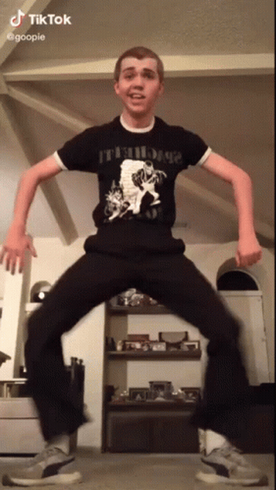 A Young Man In A Black Shirt And Black Pants Is Dancing In A Living Room . GIF