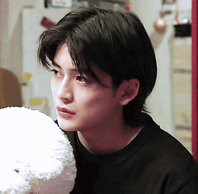 A Young Man In A Black Shirt Holds A Stuffed Animal GIF