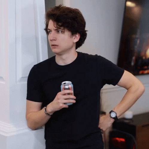 A Young Man In A Black Shirt Is Holding A Can Of Soda GIF