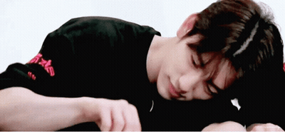 A Young Man In A Black Shirt Is Laying On His Stomach . GIF