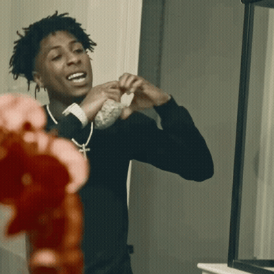 A Young Man In A Black Shirt Is Looking At Himself In The Mirror GIF