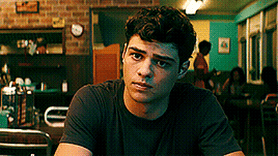 A Young Man In A Black Shirt Is Sitting At A Table In A Restaurant . GIF