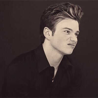 A Young Man In A Black Shirt Is Smiling GIF