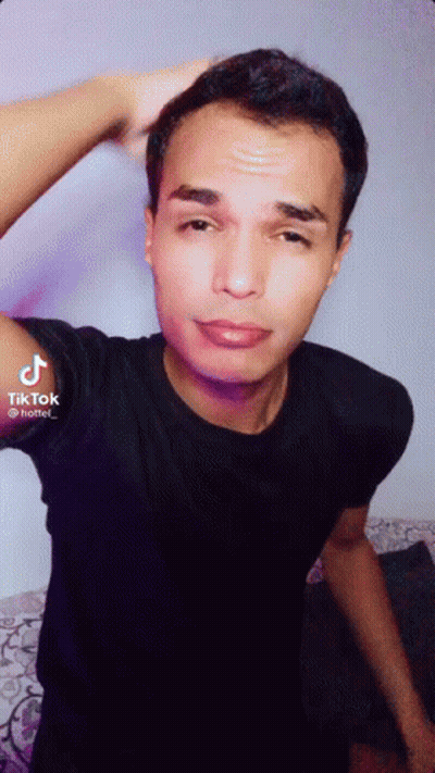 A Young Man In A Black Shirt Is Taking A Selfie . GIF
