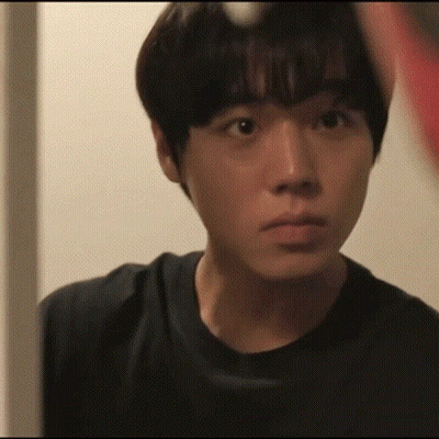 A Young Man In A Black Shirt Looks At Himself In A Mirror GIF