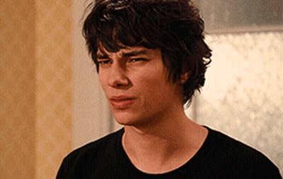 A Young Man In A Black Shirt Looks At The Camera With A Serious Look On His Face GIF