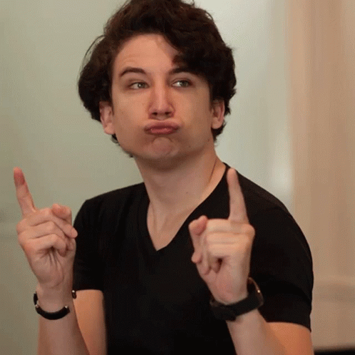 A Young Man In A Black Shirt Making A Funny Face With His Fingers GIF