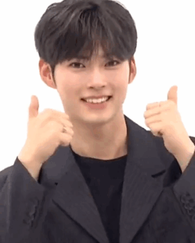 A Young Man In A Black Suit Is Giving A Thumbs Up . GIF