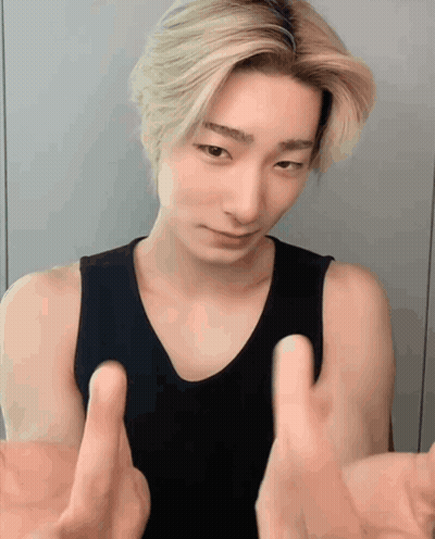 A Young Man In A Black Tank Top Is Making A Funny Face With His Hands Outstretched GIF