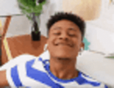 A Young Man In A Blue And White Striped Shirt Is Laying On A Couch With His Eyes Closed And Smiling . GIF