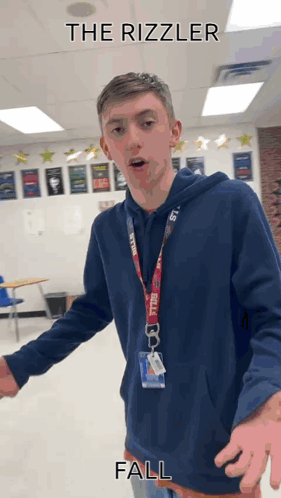 A Young Man In A Blue Hoodie Is Standing In A Classroom With The Words " The Rizzler Fall " Written Above Him GIF