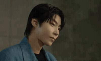 A Young Man In A Blue Jacket Is Looking Down . GIF