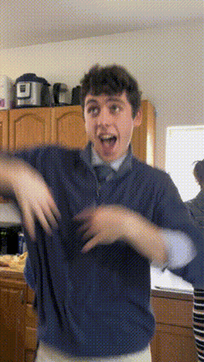 A Young Man In A Blue Shirt And Tie Is Dancing In A Kitchen GIF