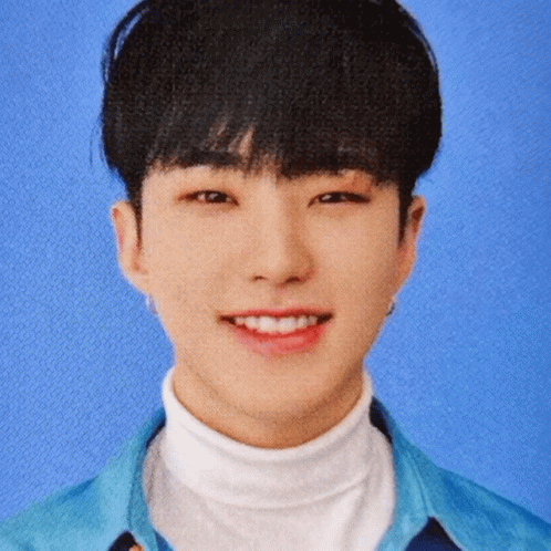 A Young Man In A Blue Shirt And White Turtleneck Smiles GIF