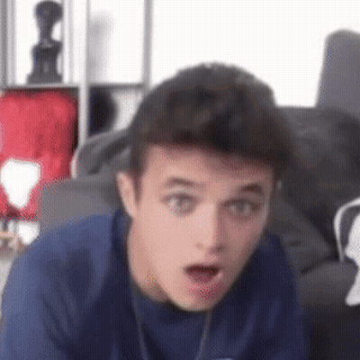 A Young Man In A Blue Shirt Is Making A Surprised Face . GIF