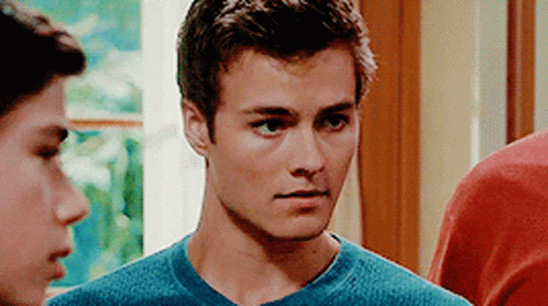 A Young Man In A Blue Shirt Is Standing Next To Another Young Man . GIF
