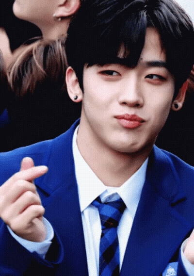 A Young Man In A Blue Suit And Tie Is Making A Heart Shape With His Finger GIF