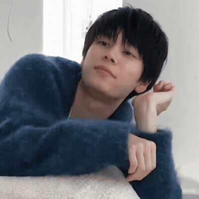 A Young Man In A Blue Sweater Rests His Head On A Pillow GIF