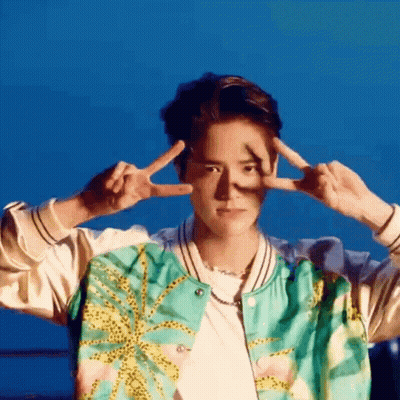A Young Man In A Bomber Jacket Is Making A Peace Sign With His Hands . GIF