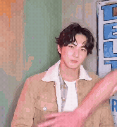 A Young Man In A Brown Jacket Is Being Hugged By A Person . GIF