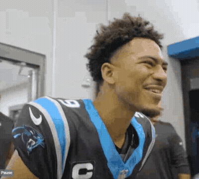 A Young Man In A Carolina Panthers Uniform Is Smiling And Laughing . GIF