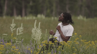 A Young Man In A Field Of Flowers Wearing A Boy Shirt GIF