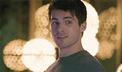 A Young Man In A Grey Shirt Looks At The Camera GIF