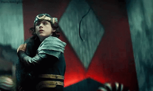 A Young Man In A Knight 'S Armor Is Holding A Sword In Front Of A Red Wall . GIF