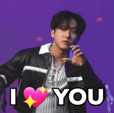 A Young Man In A Leather Jacket Is Holding A Pink Heart And Says `` I Love You '' . GIF