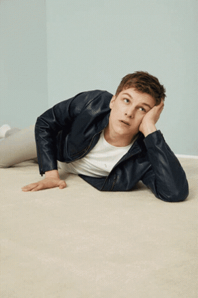 A Young Man In A Leather Jacket Is Laying On The Floor With His Hand On His Face GIF