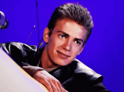 A Young Man In A Leather Jacket Is Leaning On A Table And Smiling . GIF