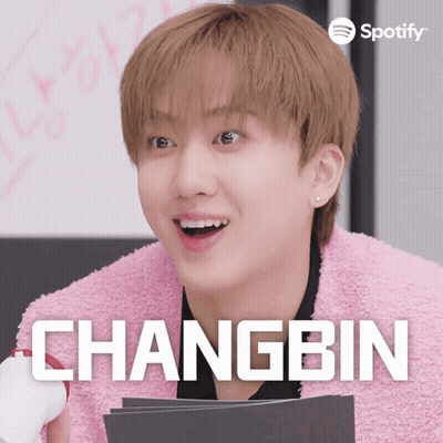 A Young Man In A Pink Jacket With The Name Changbin On The Bottom GIF