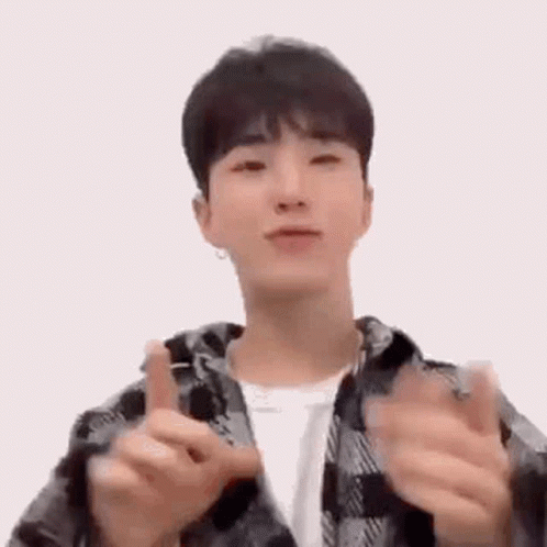 A Young Man In A Plaid Jacket Is Making A Heart Shape With His Hands . GIF