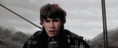 A Young Man In A Plaid Jacket Is Standing In Front Of Mountains GIF