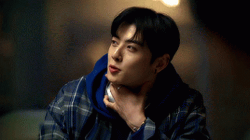 A Young Man In A Plaid Shirt Is Holding His Hand To His Chin . GIF