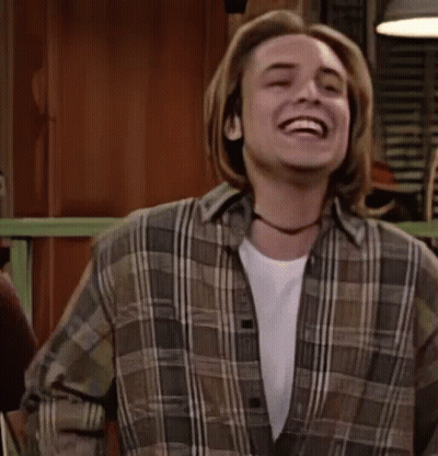 A Young Man In A Plaid Shirt Is Laughing And Dancing . GIF