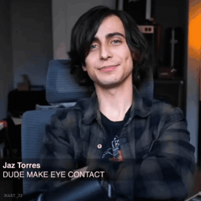 A Young Man In A Plaid Shirt Is Sitting In A Chair And Smiling With The Caption " Dude Make Eye Contact " GIF